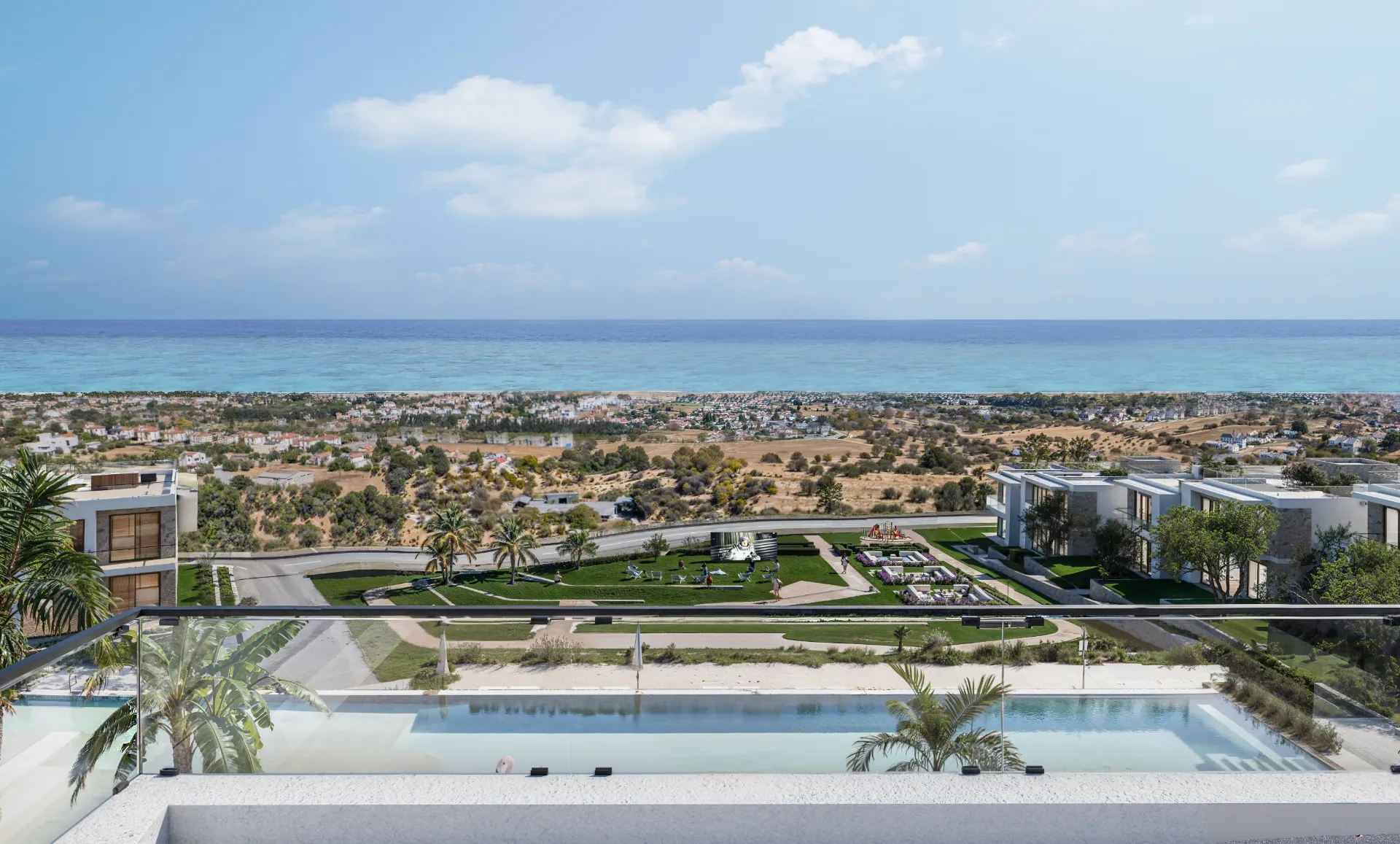 A panoramic view from a modern luxury penthouse balcony at Aura Residence in Karşıyaka, North Cyprus. The foreground features a sleek glass railing overlooking a large infinity pool and landscaped gardens. The middle ground shows a coastal road and residential villas, leading to the bright turquoise waters of the Mediterranean Sea.