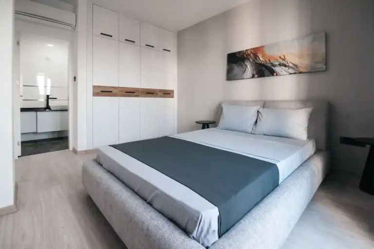 Bright, airy bedroom featuring a large bed, white walls, and contemporary artwork.