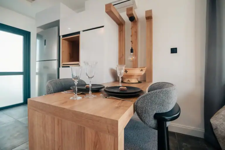 Contemporary dining space featuring a wooden table, elegant glassware, and modern chairs in a bright, stylish apartment setti.