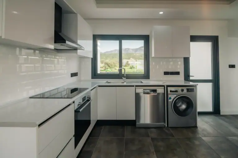 Bright contemporary kitchen featuring white cabinets, stainless steel appliances, and scenic mountain views through large win.
