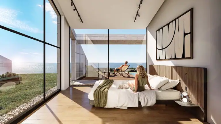 Spacious bedroom with large glass windows overlooking the sea in a North Cyprus property. Bright, modern interior with a rela.