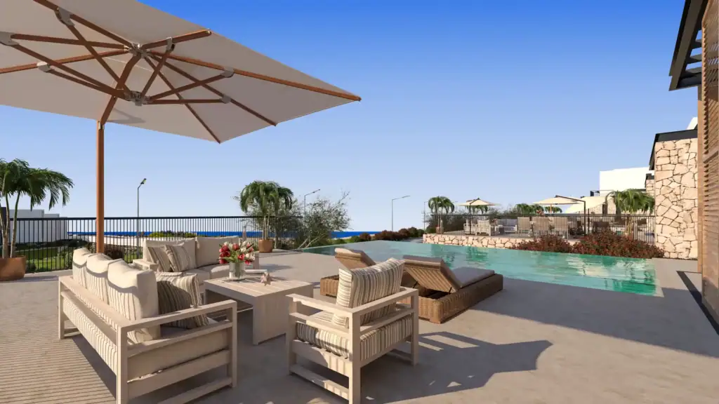 Poolside terrace with outdoor seating and umbrellas overlooking the sea in North Cyprus development.