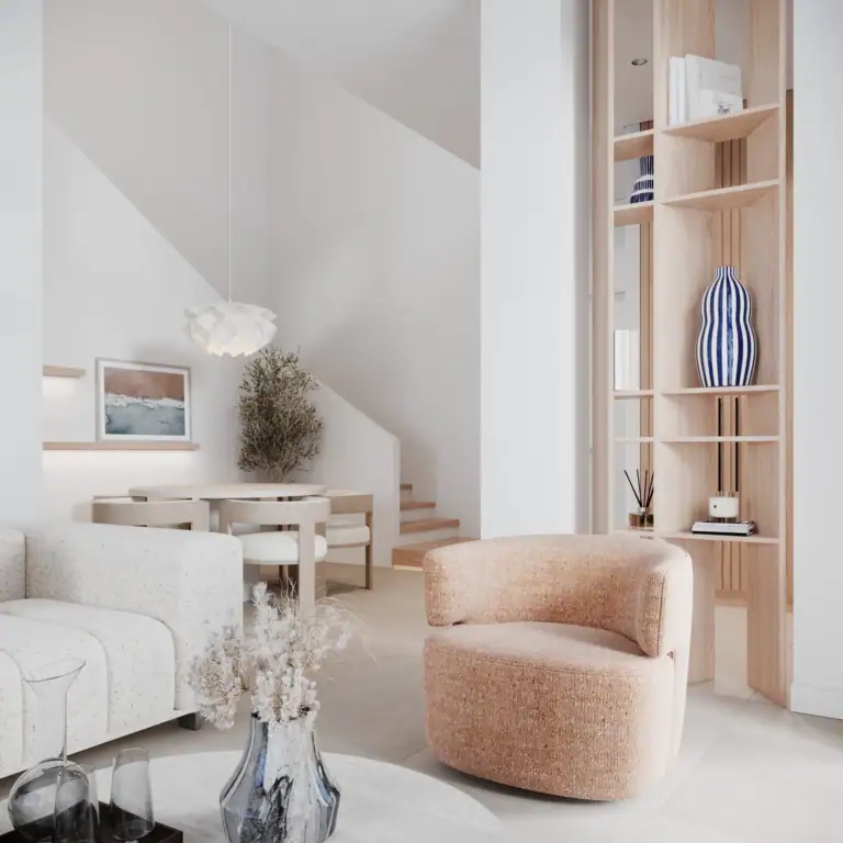 A bright, minimalist living room with a textured cream sofa, a peach armchair, a wooden bookshelf divider, and a dining area in the background.