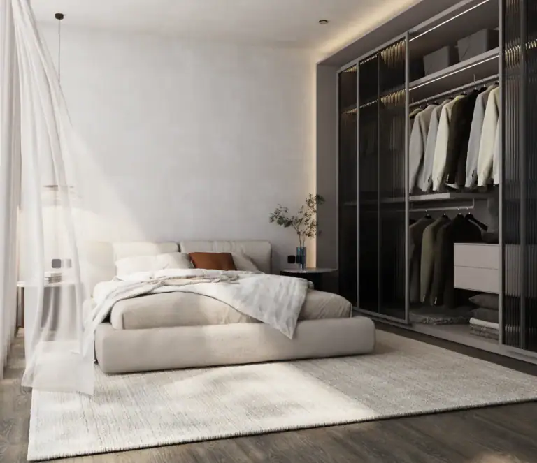 Modern minimalist bedroom in neutral beige tones with a low platform bed, a soft textured rug, and a large built-in wardrobe.