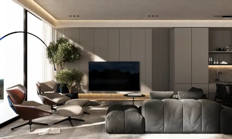 Modern luxury living room in neutral tones with a large wall-mounted TV, plush gray sectional, elegant lounge chairs, and indoor trees.