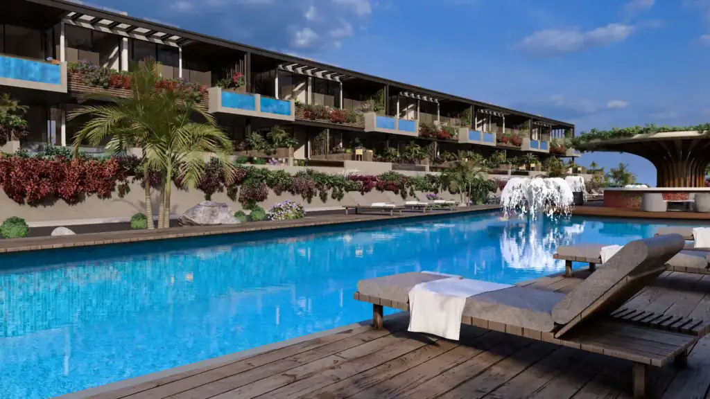 A large, crystal-clear swimming pool with a wooden deck, comfortable loungers, and a modern multi-story residential building with lush greenery.