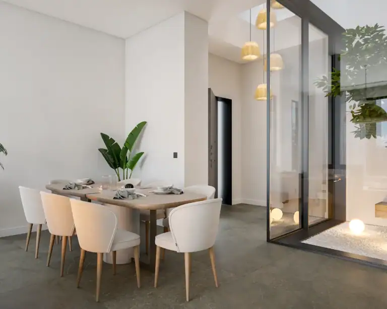 Contemporary dining room featuring a sleek table, stylish chairs, and large glass doors opening to outdoor space.