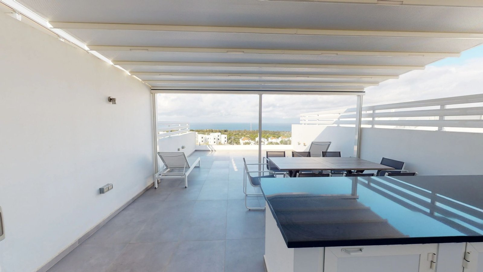 Modern rooftop terrace with seating area and panoramic views of North Cyprus coastline.